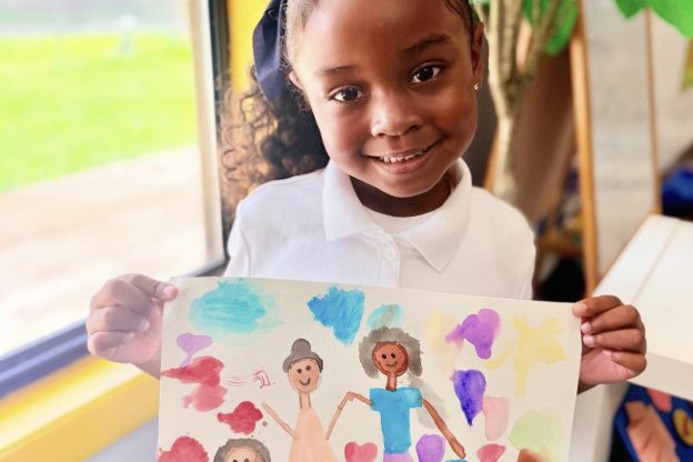 Niña sonriente mostrando su pintura de acuarela de su familia