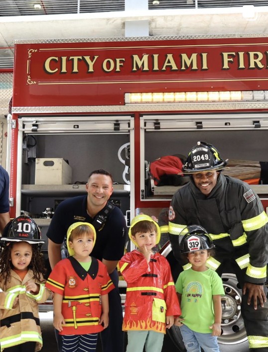 Niños de Tiniciti con bomberos de la Ciudad de Miami frente al camión