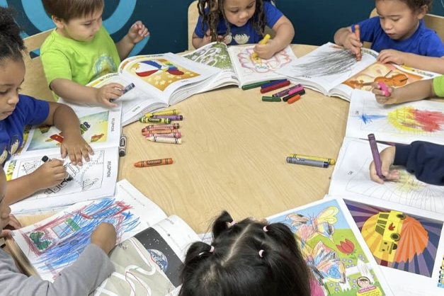 Grupo de niños coloreando juntos alrededor de una mesa redonda
