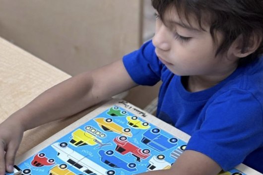 Niño concentrado armando un rompecabezas de carros