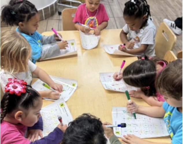 Niños escribiendo con marcadores en sus hojas de trabajo
