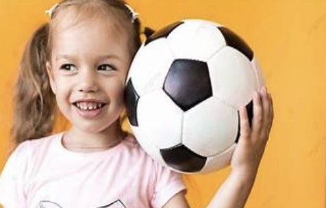 Niña sonriendo con un balón de fútbol