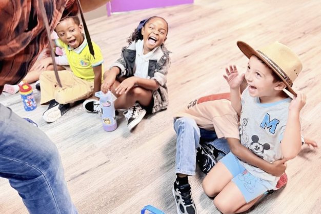 Niños sentados en el piso cantando y bailando en la clase de música