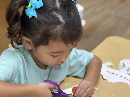 Niña recortando su dibujo con tijeras de seguridad